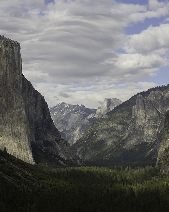 Photo color enhancement service of Yosemite Valley with granite cliffs and forested valley floor under a cloudy sky.