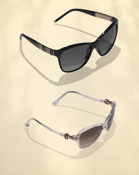 Two pairs of sunglasses, black and white, on a light beige background with visible shadows.
