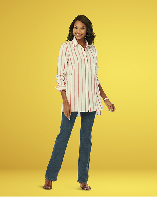 African American woman smiling, wearing a striped shirt and jeans, standing against a yellow background.