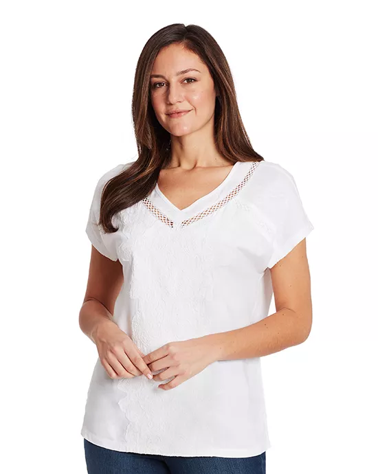 Woman in white V-neck blouse and blue jeans posing confidently for Image Resizing Services.