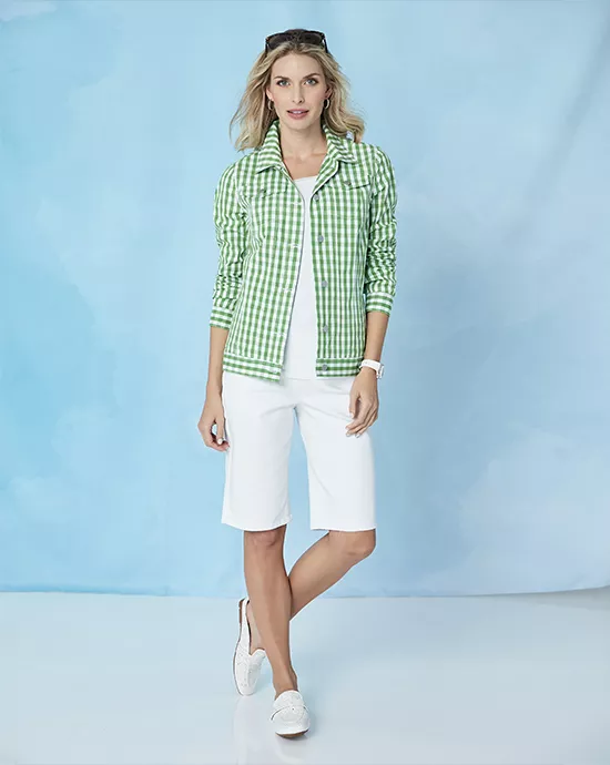 Woman modeling a green and white gingham jacket with matching shoes, white top, and knee-length shorts against a blue backdrop.