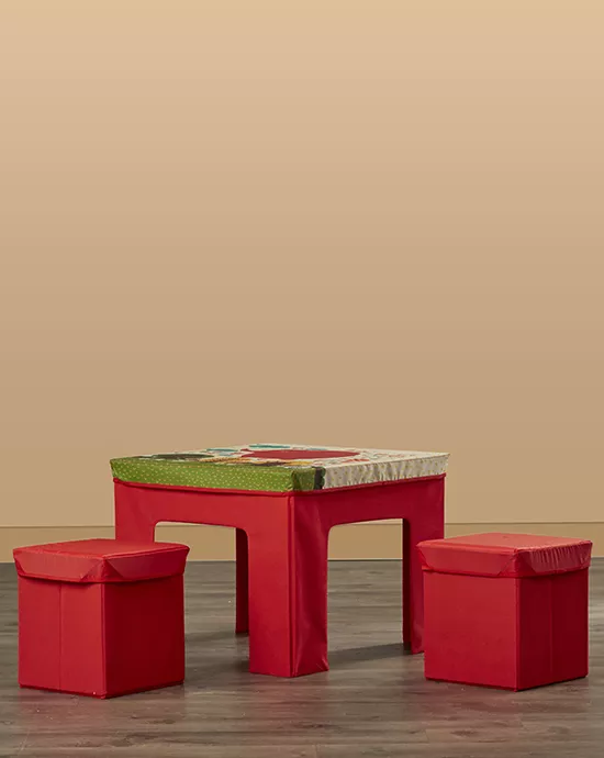 Red table with colorful tabletop and two matching stools on beige background.
