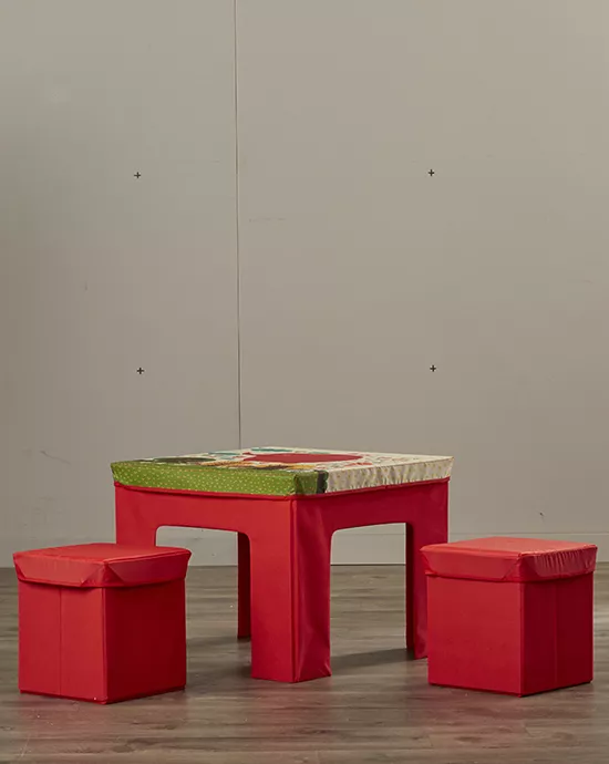 Red children's table with patterned top and three matching stools on grey background.