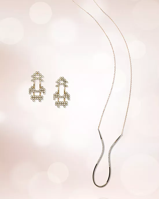 Elegant earrings and a matching pendant necklace displayed on a soft, glowing background.