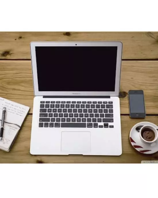 A laptop, smartphone, coffee cup, and scattered notes neatly arranged on a wooden table surface.