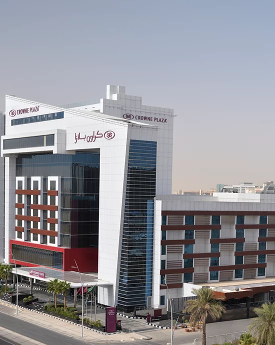 Modern Crowne Plaza hotel with glass and red panel façade in urban setting.