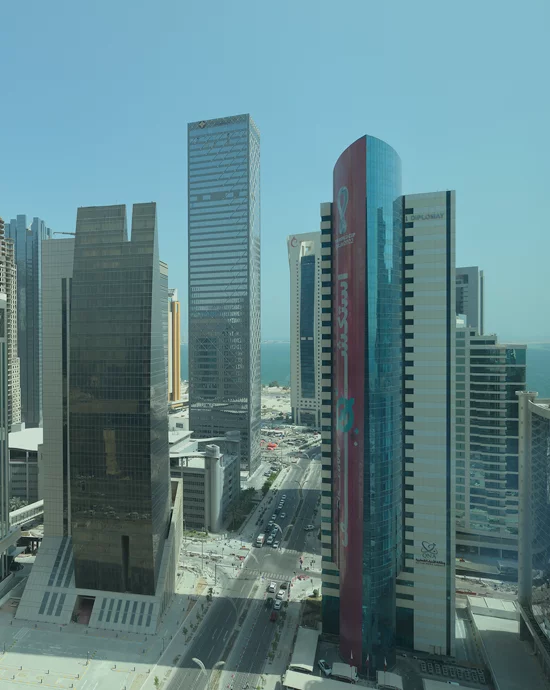 Aerial view of modern cityscape with skyscrapers and busy streets near coastline.
