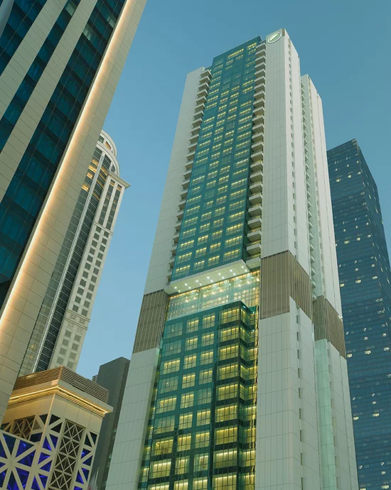 Tall modern skyscrapers with illuminated windows at dusk – Professional photo retouching services.
