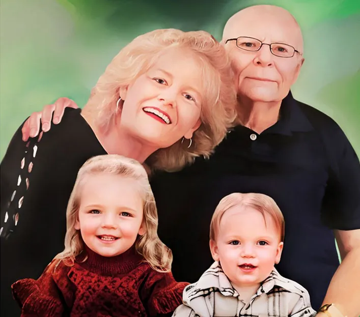 Family portrait of a smiling elderly couple with two young grandchildren against a soft green background.